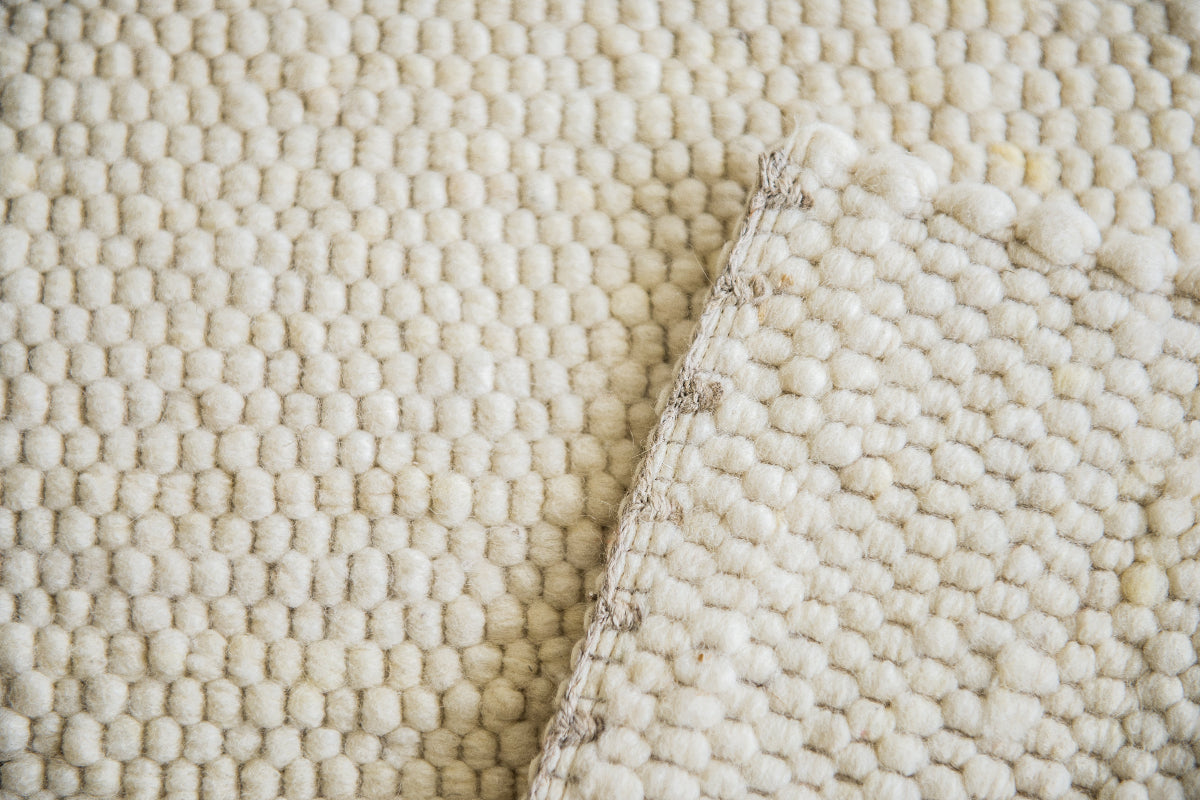 Close-up van Texelkleed Branding, gemaakt van witte Texelse schapenwol, met nadruk op de afwerking van de randen.