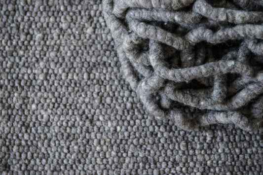 Close-up van Texelkleed Slufter, samen met de garen waarvan het is geweven, gemaakt van 50% witte en 50% blauwe Texelse schapenwol.