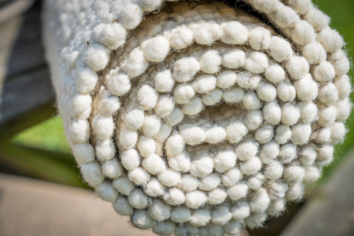 Close-up van Texelkleed Strand opgerold, gemaakt van witte Texelse schapenwol. met een beetje blauw erbij.